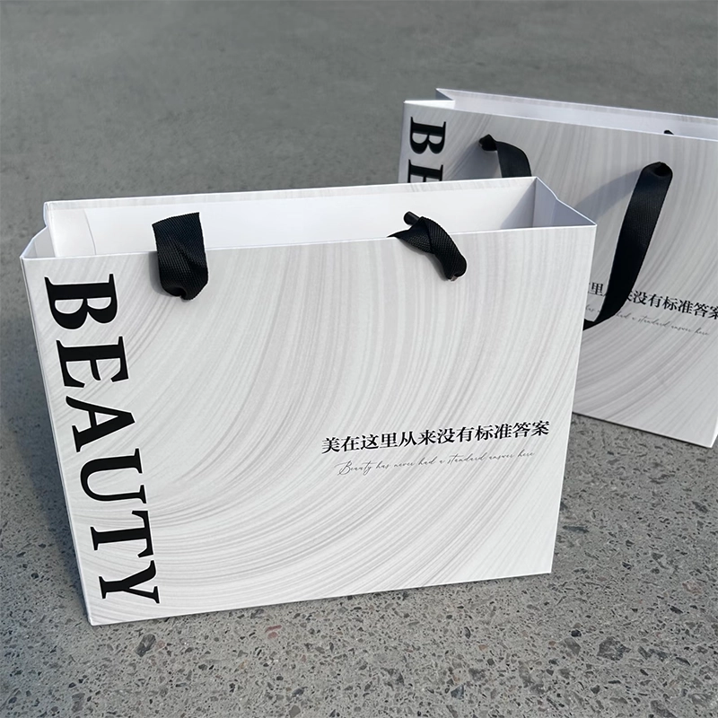 White cosmetic paper bag with black ribbon handles for a minimalist beauty brand